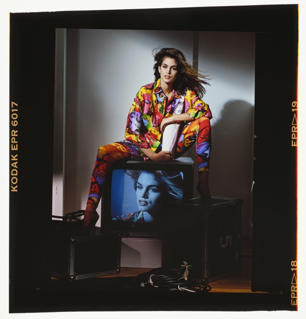 Rico Puhlmann, Cindy Crawford mit Seidenhemd mit Marilyn Monroe-Print und abstrakt gemusterte Leggins von Gianni Versace, 1991, Farbdiapositiv, 4,2 x 5,6 cm, © Rico Puhlmann Archive (veröffentlicht in „Signature Style“, Harper’s Bazaar (USA), Nr. 3351, March 1991)