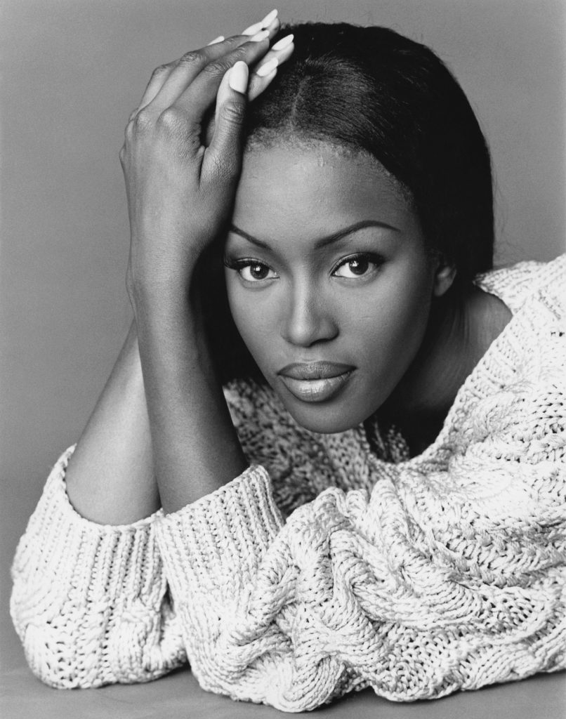 Rico Puhlmann, Naomi Campbell (mit beigefarbenem oversized Seidenpullover mit Zopfmuster von Michael Kors), 1992, Silbergelatinepapier, 50,5 x 40,6 cm, © Rico Puhlmann Archive(veröffentlicht in „10 Most Beautiful Women“, Harper’s Bazaar (USA), Nr. 3366, June 1992)